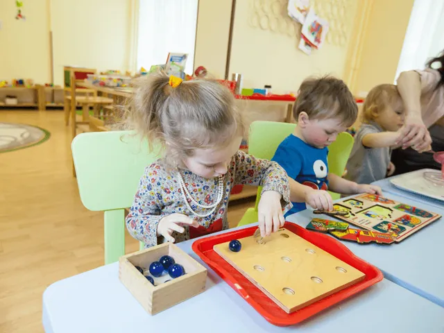 Zwei kleine Kinder arbeiten an einem Tisch mit Holzmaterial in einem hellen Gruppenraum