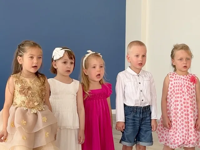 Fünf jüngere Kinder stehen nebeneinander und singen
